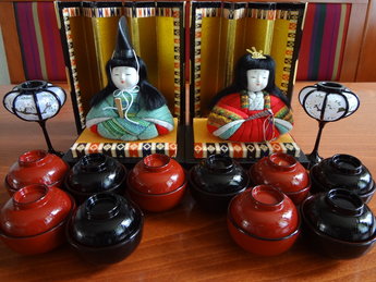Hina Doll set Hokkaido Japanse Poppen Japan Vintage  Elk jaar op 3 maart wordt de Hina Matsuri, ook wel Doll Festival gevierd. Op deze dag wensen families met meisjes hun dochters een succesvol en gelukkig leven. Op verschillende platforms worden poppen neergezet, met bovenaan voor een gouden achtergrond de keizer en keizerin. Dit festival vindt zijn oorsprong in een Chinese gewoonte waarbij ongeluk overgedragen wordt aan poppen. De poppen die hiervoor gebruikt worden zijn vaak al heel oud, overgegeven van generatie op generatie. Het eten dat geofferd wordt aan de poppen bestaat onder andere uit diamantvormige rijstwafels, hartvormig snoep en er wordt zoete sake gedronken.  Veel mensen zetten kleine platforms neer bij gebrek aan ruimte